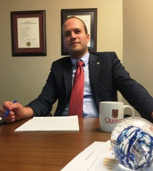 Nate Erskine-Smith, Law’10 (Arstci’07), sitting at his office desk, where his Dan Soberman Outstanding Young Alumni Award is proudly displayed